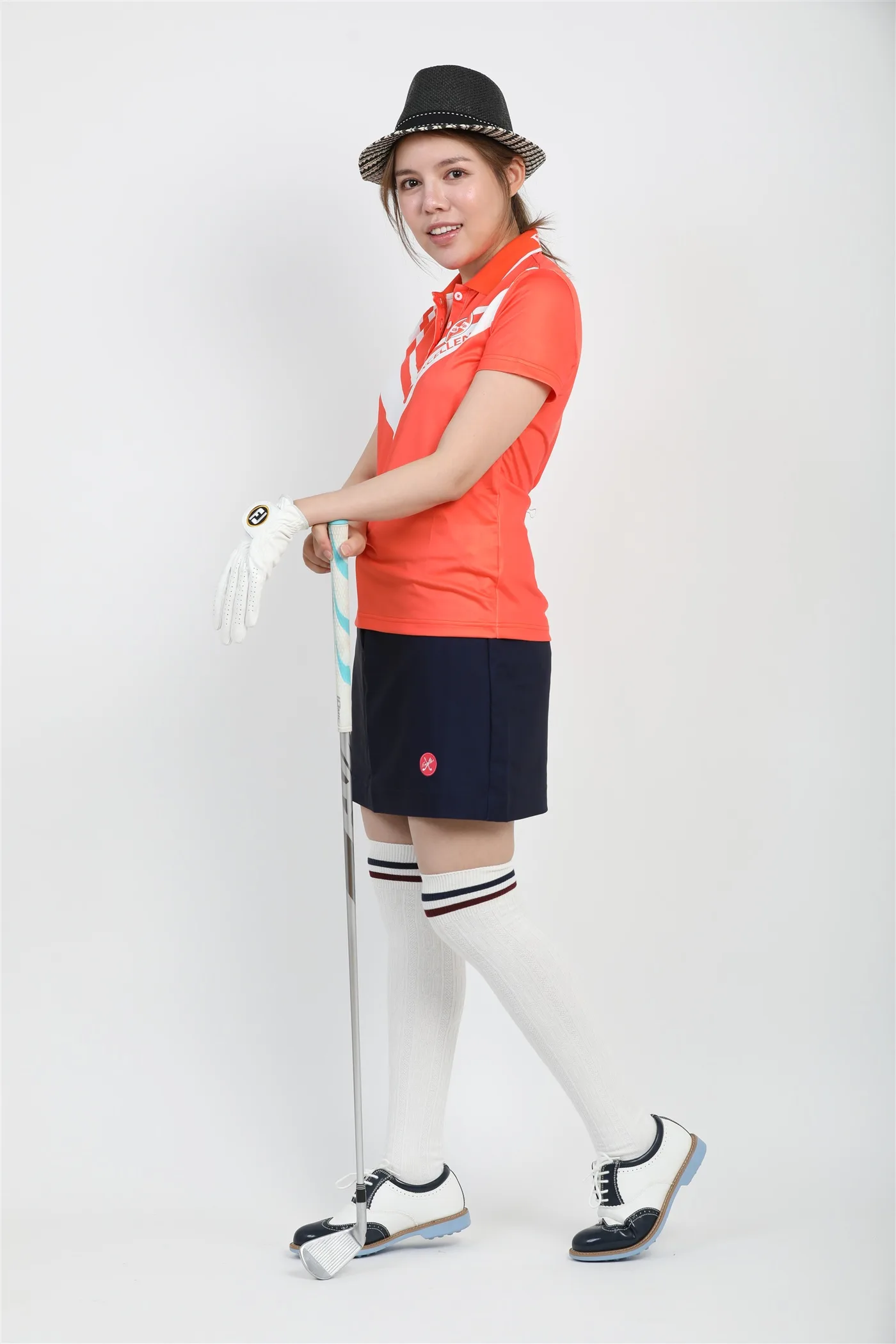 Excellent golfのオレンジポロとネイビースカートを使ったレディースコーディネート